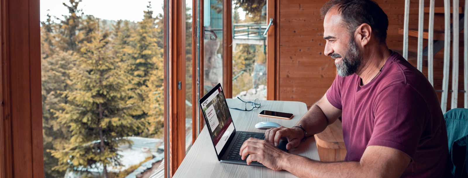 Man exploring First National Bank & Trust website with wooded view